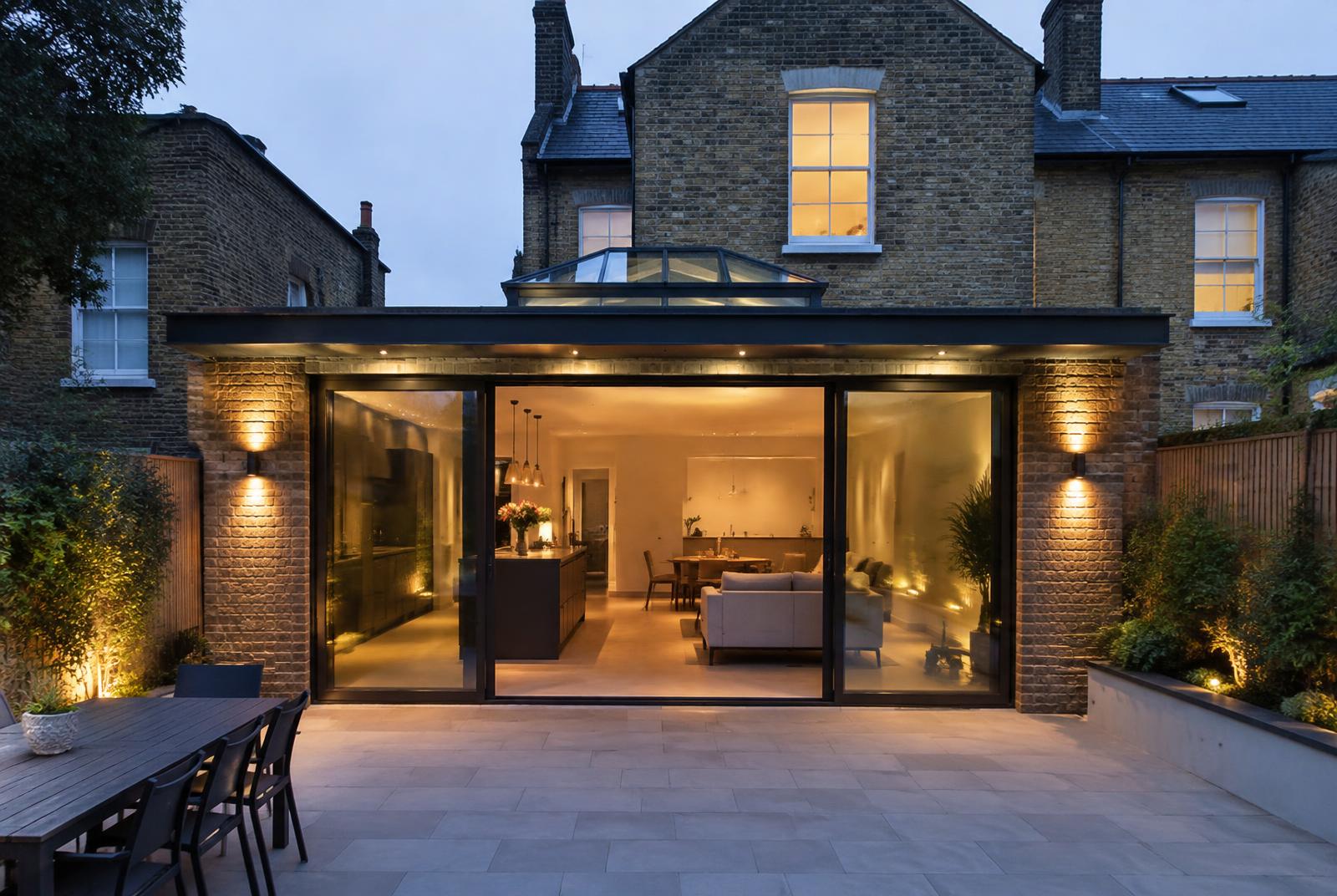 Finished contemporary rear extension with sliding doors lit at dusk